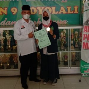 Kepala MTsN 9 Boyolali menyerahkan medali emas dan uang pembinaan kepada Alisyah Fitriani Juara I turnamen VII Seni Tapak suci virtual tingkat pelajar se Jawa Tengah